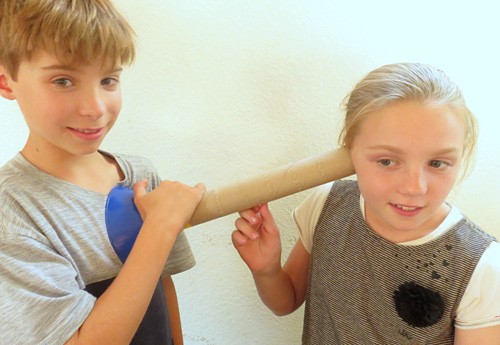 Photo of a child using a cardboard tube and inverted funnel to listen to the heartbeat of another child