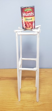 A paper tower with a rectangular frame and a can of beans at the top.