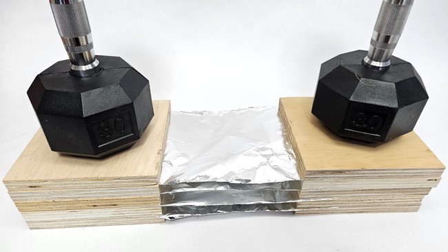 Model plywood and aluminum foil Whipple shield with dumbbells placed on top