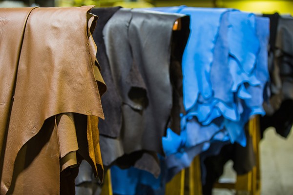 Piles of brown, blue, and black sheets of leather at a leather tannery. 