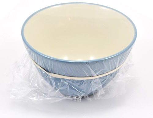 Plastic wrap is stretched across the top of a small bowl and secured with a rubber band