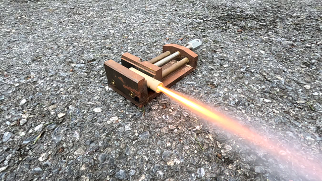 An estes A8-3 model rocket engine clamped into a heavy vise
