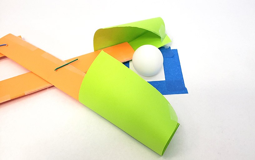 A scissor-left mechanism with two paper scoopers on the end to grab a ping pong ball 