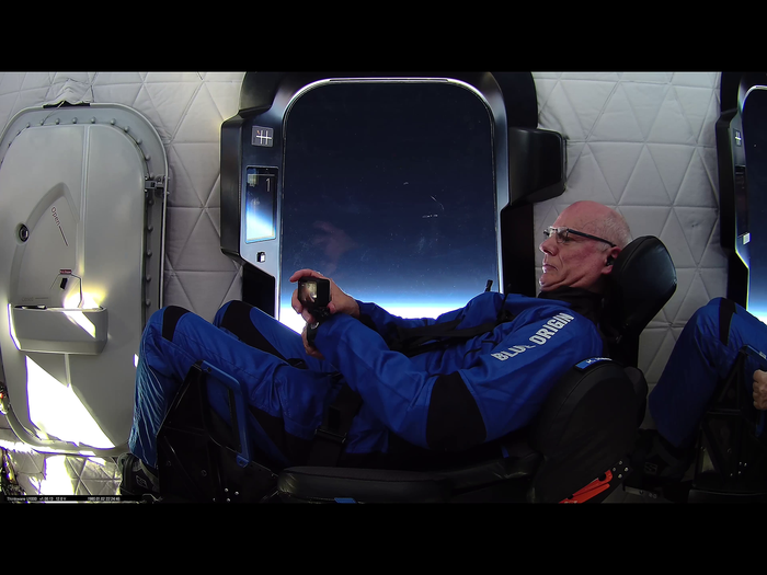 Ken crew strapped in during takeoff and ascent and checking wrist-mounted camera