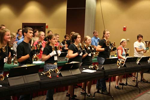 A room full of people practice playing the handbell