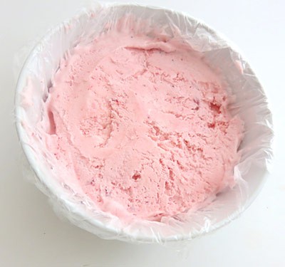 Pink ice cream fills a bowl lined in plastic wrap