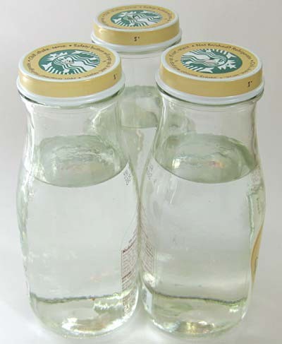 Three glass bottles filled with water are placed in a triangle formation so the walls of the bottles touch