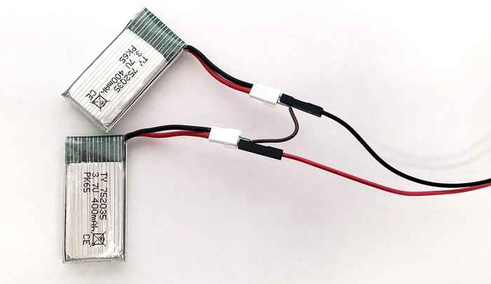 Two small lithium batteries, with the positive wire of one battery connected to the negative end of the next battery with a jumper wire, putting them in series. The remaining battery wires are connected to the two motor wires.