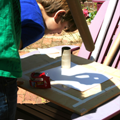 Young student looking into a pinhole camera