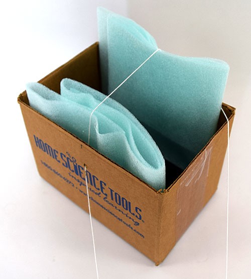 Cardboard box with foam padding, a phone inside, and string poked through holes in opposite edges
