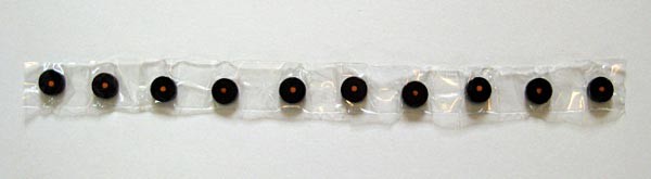 Ten circular magnets are lined up in the same polar direction and laid on a long strip of clear tape