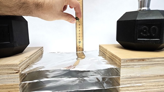 Meter stick set up to measure marble drop height for Whipple shield test