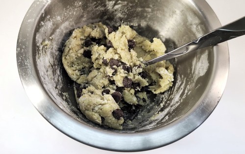 Large mixing bowl with cookie batter with chocolate chips mixed in.