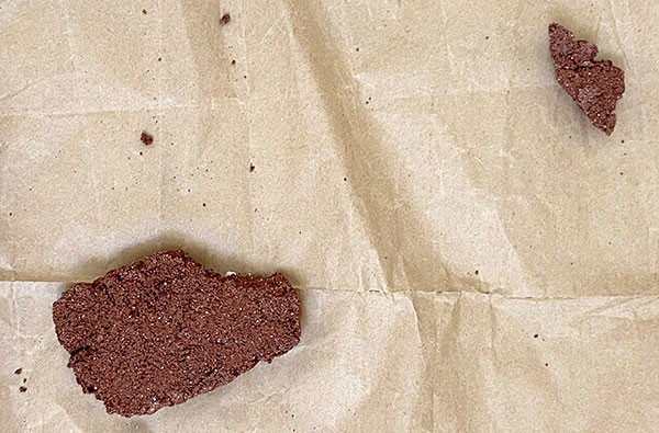 A brick and a corner that has broken off on brown paper.