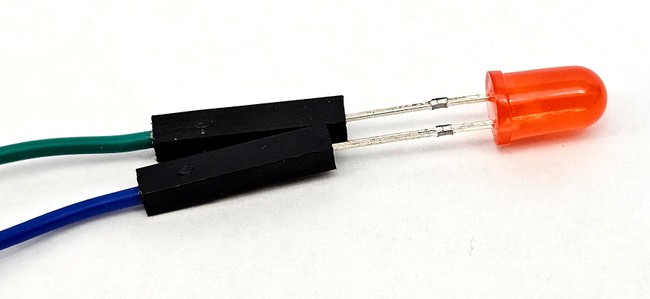An LED with its two legs pressed into female jumper wires