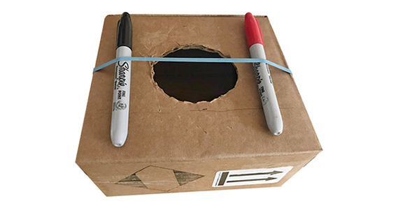 Cardboard box with markers and rubber bands for a simple guitar