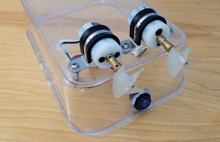 Upside-down plastic container with two motors bolted to the bottom