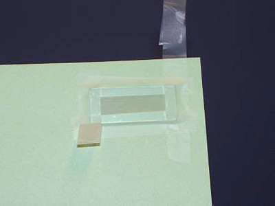 Glass slide with all four edges taped to form a well in the middle. 