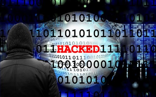 Image of a hooded figure looking at lines of binary code with the word 'hacked' highlighted in red