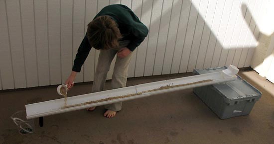 Sand is sprinkled evenly across the inside of a rain gutter