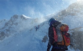 A climber at the base of a snowy mountain