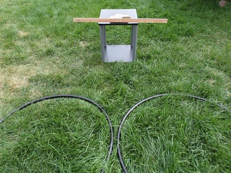 Two hula hoops lying in the grass in front of a yard stick.