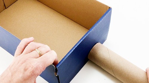 A shoebox that is about 3 tiome as heigh as a cardboard tube.