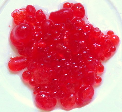 A bowl is filled with small balls of red gelatin