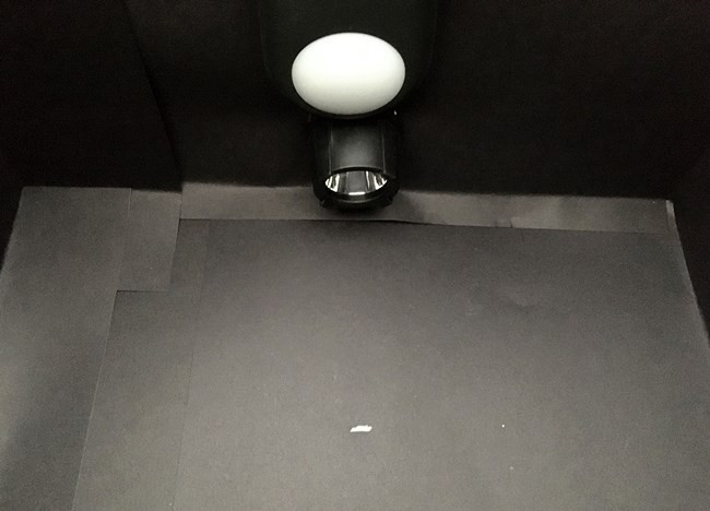 The inside of test box with a short line drawn on the bottom black paper in front of the light source.