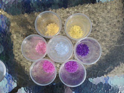 Clear plastic cups with various colors of ultraviolet beads.