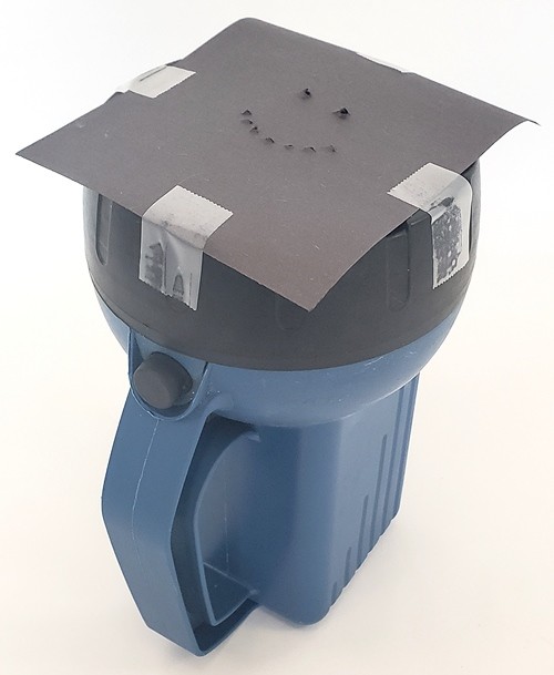 A flashlight with a piece of construction paper with holes in it taped over the front. 
