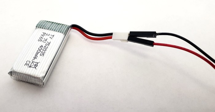 A small lithium battery with red and black wires connected to the red and black wires from the motor.