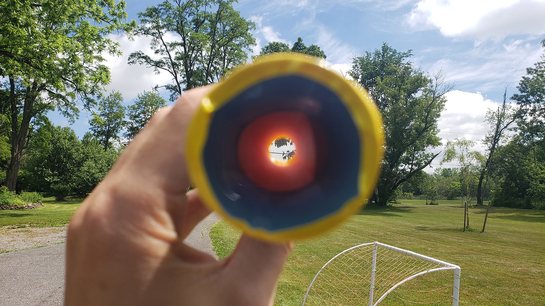 Scenery with trees, clouds, and a power line. Part of the picture shows the view through the telescope, where the leaves and power line are magnified.