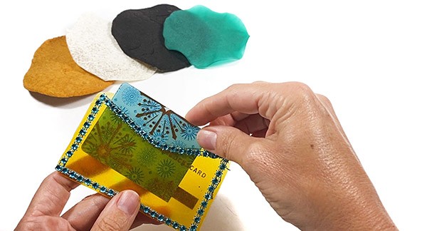  Four different biofabric patches made from different materials. A hand is placing a card in a credit card wallet made from alginate biofabrics.