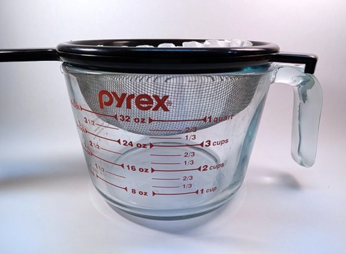 Coffee filter in a strainer over a large cup viewed from the side