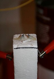 Two nails stick out of the side of a block of styrofoam