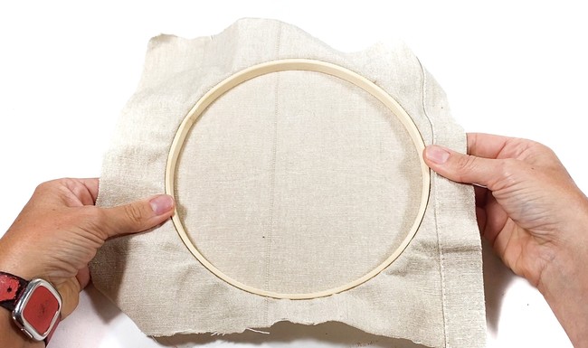A wooden embroidery hoop with canvas inside. 
