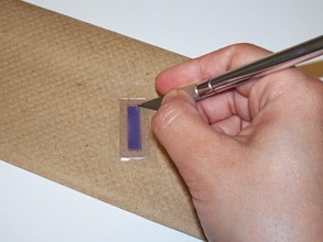 Cutting a rectangle of parafilm from the top of a glass slide with a utility knife.  
