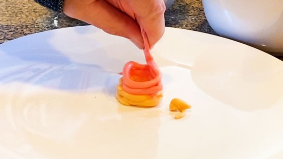 A second layer of red icing being placed on tower of two layers of yellow icing.