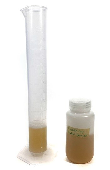 A measuring cylinder filled with 50 mL of liquid. A bottle filled with liquid stands next to the measuring cylinder.