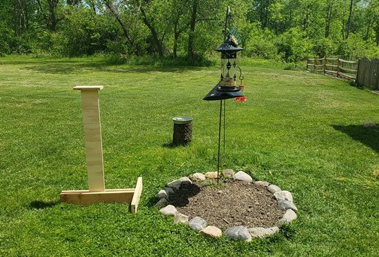  A wooden post next to a bird feeder. 